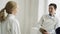 Two young smiling fencers man and woman sharing experience during break of fencing match indoors