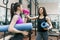 Two young smiling fitness women talking with sport mats in the gym. Training, teamwork, healthy lifestyle concept