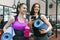 Two young smiling fitness women talking with sport mats in the gym. Training, teamwork, healthy lifestyle concept