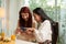 Two young smiling women in smart casualwear looking at smartphone screen