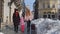 Two young smiling women tourists with adoption child girl walking with suitcase on old city streets