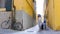 Two young smiling women walking through the narrow yellow streets with luggage