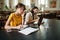 Two young students making study notes with laptop in library of university