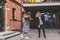 Two young stylish women in medical masks dancing and having fun while walking the street in town. Friends strolling