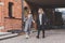 Two young stylish women in medical masks talking and laughing while walking the street in town. Friends strolling