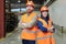 Two young successful engineers in hardhats and orange workwear