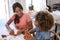 Two young teen and pre-teen girlfriends sitting at a table at home playing with modelling clay, close up, elevated view