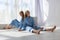 Two young twin girls in identical blue suits sitting on white cyclorama floor in studio in pattern of light and shadow