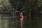 Two young woman adventurous people having fun together while red kayaking on brook in forest