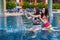 Two young woman friends splashing water in swimming pool