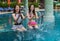 Two young woman friends splashing water in swimming pool