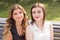 Two young woman sisters sitting on a bench in a park