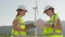 Two young women alternative energy professionals ensure the stability of green energy production near windmill electric