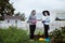 Two young women in the background of a garden with gloves and tools with a field of beds