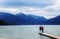 Two young women from behind stand on a jetty in the tegernsee lake