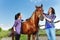 Two young women brushing bay horse at the farm