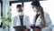 Two young women doctor wearing a hygienic facial mask talking while working digital tablet in hospital.