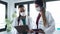 Two young women doctor wearing a hygienic facial mask talking while working digital tablet in hospital.