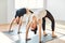 Two young women doing yoga asana upward bow wheel pose