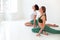 Two young women doing yoga indoor, sitting in position  over white studio background