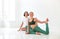 Two young women doing yoga indoor, sitting in position  over white studio background