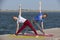 Two young women doing yoga at nature. Fitness, sport, yoga and healthy lifestyle concept - group of people making yoga pose on