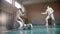 Two young women fencers having a training in the gym - gear on the foreground