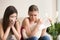 Two young women friends crying together at home