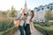 Two young women having fun, looking at the smartphone laughing, sunny autumn day, city background, golden hour