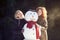 Two young women hugging snowman