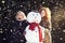 Two young women hugging snowman