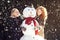 Two young women hugging snowman