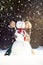 Two young women hugging snowman