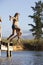 Two Young Women Jumping From Jetty Into Lake