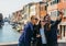 Two young women and man capture a happy selfie on a bridge in Murano near Venice, Italy