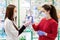 Two young women in medical masks and gloves on the background of a window with pharmacy products, choose a medicine. The concept