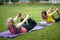 Two young women performs training for flexibility in the park