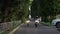 Two young women in protective helmets slowly riding motorcycles on narrow road