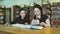 Two young women reading textbooks at library