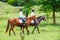 Two young women riding horse in park.