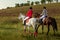 Two young women riding horse in park. Horse walk in summer