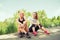 Two young women seating outdoors in a park on sunny summer day