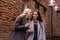 Two young women are secreting about something in the courtyard of an old building