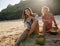 Two young women sitting on the beach and smiling