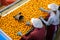 Two young women sorts tangerines on a conveyor line. Fruit quality check. Top view.