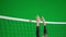 Two young women in sportswear playing volleyball on green screen chroma key. One athlete hits the ball and the other
