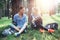 Two young women in sportswear sitting under trees in the forest drinking water, talking and resting after training