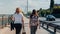 Two young women in street clothes are walking on the waterfront along the water.