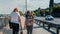 Two young women in street clothes are walking on the waterfront along the water.