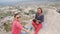 Two young women traveler sits on the edge of the mountain and taking a selfie